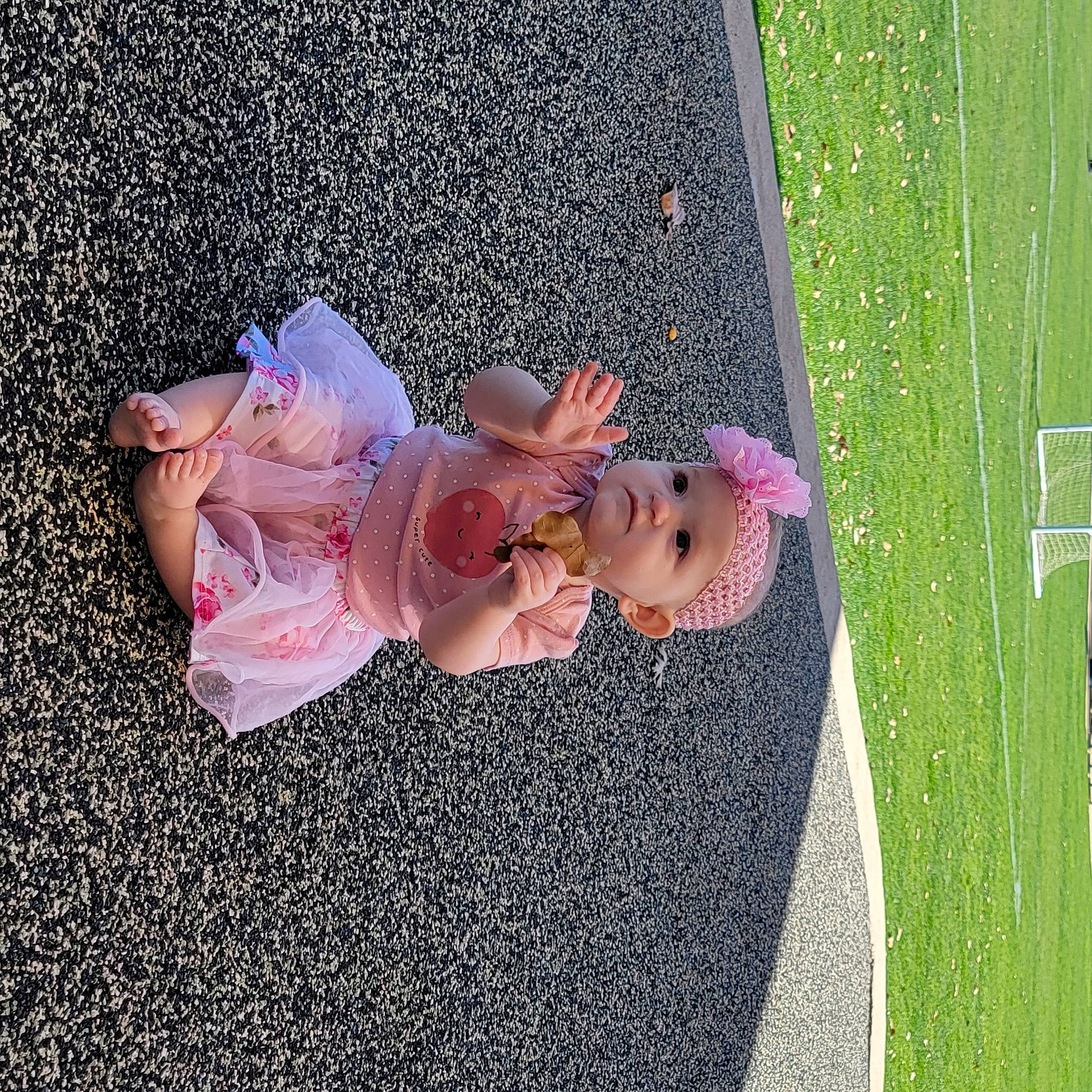 Abigail is registered to the contest to win money with this photo: asphalt, dress, flower, fun, gesture, grass, happy, headwear, leisure, organism, people_in_nature, person, petal, pink, plant, recreation, road_surface, shrub, spring, toddler