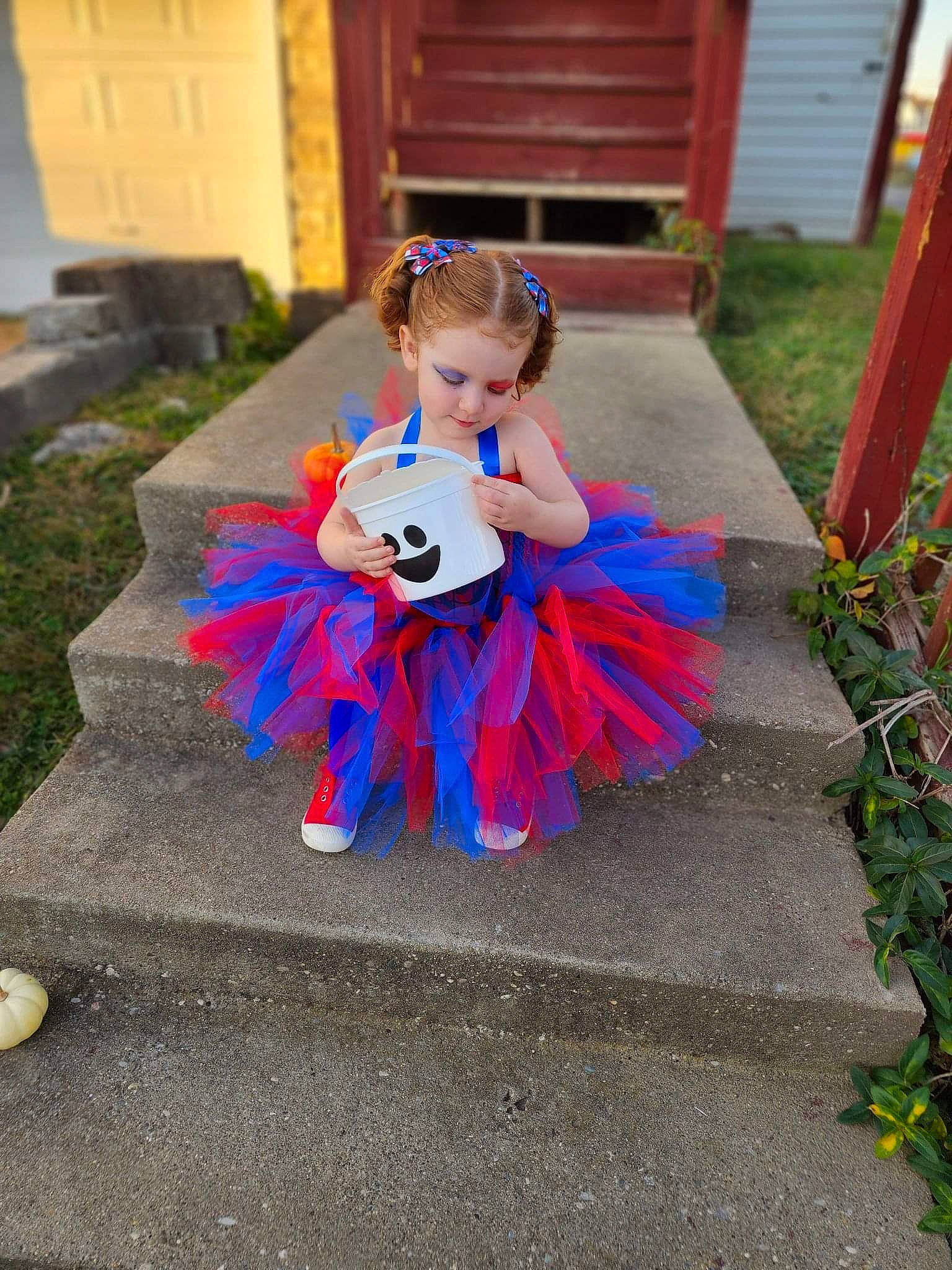 Rosemary is registered to the contest to win money with this photo: asphalt, baby_toddler_clothing, child, costume, dress, electric_blue, event, flooring, garden, grass, magenta, person, plant, pumpkin, road_surface, sidewalk, sitting, toddler, toy, wood