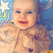 Antonia joined the competition — help win amazing prizes! baby, smiling, blue_eyes, onesie, pink_clothing, dog_pattern, infant, happy, cute, lying_down, blanket, stars, cartoon, face, child, portrait, hand, fingers, indoors, closeup