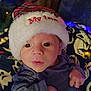 baby, celebration, child, christmas, clothing, cozy, cute, expression, face, festive_lights, hat, holiday, indoors, infant, newborn, person, portrait, santa_hat, soft_lighting, warm