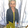 child, girl, smiling, leather_jacket, green_clothing, hair_accessories, curtains, indoor, carpet, window, standing, happy, portrait, fashion, person, cute, toddler, bright_colors, casual, home