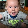 toddler, child, smiling, happy, indoor, living_room, shirt, dinosaur, text_on_clothing, person, face, eyes, hair, carpet, furniture, television, home, candid, portrait, baby
