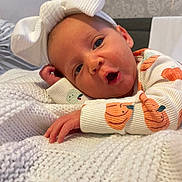 Delilah is registered to the contest to win money with this photo: baby, infant, headband, bow, knitted_blanket, orange, pumpkin, clothing, cute, face, hand, lying_down, expression, indoors, portrait, child, soft_texture, cozy, sleepwear, young