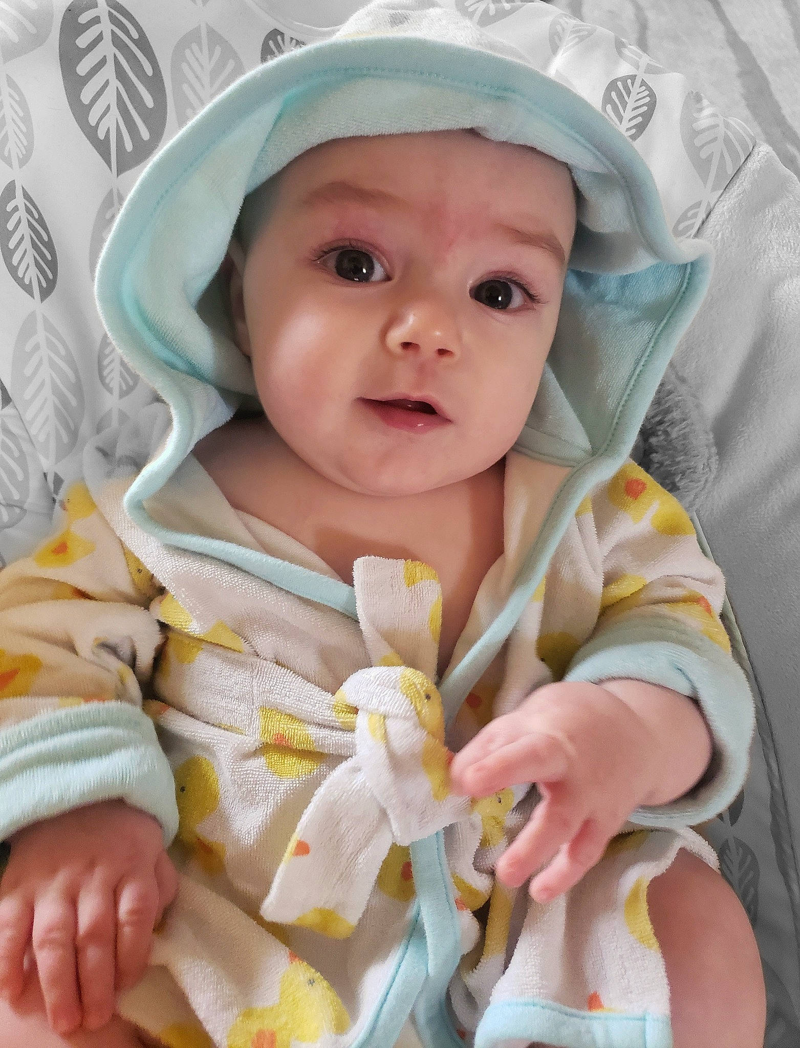 Aiden is registered to the contest to win money with this photo: baby, baby_products, baby_safety, baby_toddler_clothing, cheek, child, comfort, fashion_accessory, headwear, iris, linens, nail, pattern, peach, person, sitting, skin, surprise, thumb, toddler
