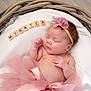 newborn, baby, sleeping, pink_tutu, flower_headband, wicker_basket, white_blanket, wooden_tiles, name_tiles, infant, cute, peaceful, portrait, soft_lighting, skin, hand, face, baby_girl, resting, decor