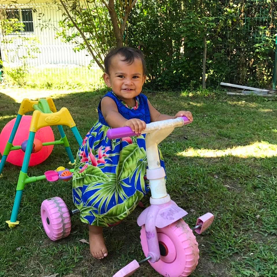 Vaihakaiki participe au concours pour gagner de l'argent avec cette photo : automotive_wheel_system, baby_toddler_clothing, child, fun, grass, happy, joy, leisure, person, pink, plant, purple, recreation, riding_toy, smile, summer, tire, toddler, toy, tree