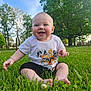 Ezra Ray is registered to the contest to win money with this photo: baby, barefoot, child, cute, daytime, face, grass, greenery, happy, infant, nature, outdoor, park, portrait, shorts, sitting, smiling, sunlight, trees, tshirt