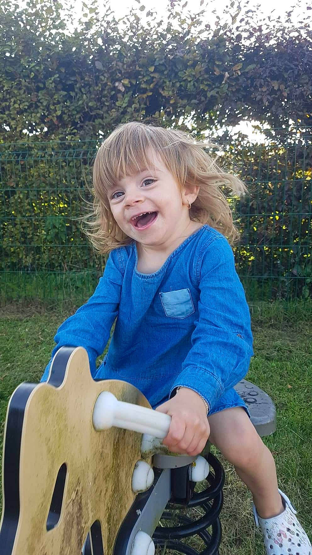 Léonie a rejoint le concours — aidez-le/la à gagner de superbes lots ! baby_toddler_clothing, blond, child, electric_blue, fun, grass, happy, lawn, leisure, musical_instrument, people_in_nature, person, plant, shoe, sitting, smile, spring, summer, toddler, tree
