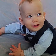 Nattan participe au concours pour gagner de l'argent avec cette photo : baby, child, infant, face, eyes, hand, clothing, shirt, vest, lying_down, cute, expression, portrait, skin, smile, person, indoors, soft_surface, curious, young