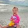 baby, barefoot, beach, child, clouds, happy, ocean, outdoor, pink_clothing, playful, rubber_duck, sand, sitting, sky, smiling, strawberry_pattern, summer, swimsuit, toy, water