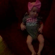 Sykora Tubbs joined the competition — help win amazing prizes! baby, bow, headband, onesie, child, infant, couch, furniture, indoor, sitting, blur, dim_light, person, soft_toy, pink, text_on_clothing, legs, feet, cute, portrait