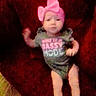 Sykora Tubbs joined the competition — help win amazing prizes! baby, child, pink_bow, onesie, sassy, couch, red_background, infant, clothing, person, indoor, cute, blurred, face, legs, sitting, expression, young, headwear, furniture