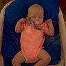 baby, infant, pacifier, sleeping, blue_cushion, orange_outfit, blanket, indoors, child, resting, cute, toddler, person, soft_lighting, baby_bed, sleep, small_arms, peaceful, clothing, head