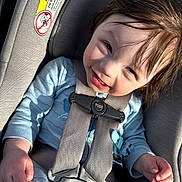 Skyler is registered to the contest to win money with this photo: toddler, child, car_seat, harness, blue_clothing, smiling, sunlight, hair, face, hand, warning_label, seatbelt, infant, safety, portrait, happy, baby, closeup, seat, indoors