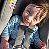 toddler, child, car_seat, harness, blue_clothing, smiling, sunlight, hair, face, hand, warning_label, seatbelt, infant, safety, portrait, happy, baby, closeup, seat, indoors