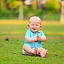baby, child, grass, outdoor, smiling, barefoot, blue_shirt, happy, clapping, sitting, nature, greenery, cute, infant, sunlight, portrait, playful, daylight, young_child, field