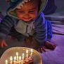 Abigaël a rejoint le concours — aidez-le/la à gagner de superbes lots ! baby, birthday_cake, blue_onesie, candles, celebration, child, clothing, cozy, cute, face, happy, indoors, infant, plate, sitting, smiling, soft_lighting, stitch_costume, toy_costume, warm_light