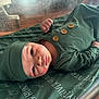 Skye joined the competition — help win amazing prizes! baby, infant, newborn, green_clothing, hat, blanket, face, skin, hand, lying_down, indoors, portrait, cute, soft_light, wood_floor, text_pattern, button, sleepwear, child, resting