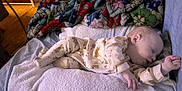 Tegan is registered to the contest to win money with this photo: baby, sleeping, pajamas, blanket, towel, bed, indoor, child, cozy, soft, animal_print, floral, colorful, peaceful, infant, resting, person, cute, warm, comfort