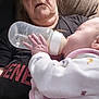 Tegan is registered to the contest to win money with this photo: baby, bottle, feeding, elderly_person, glasses, hand, indoor, person, face, clothing, chair, nurturing, care, closeup, comfort, infant, rest, human, toddler, warmth