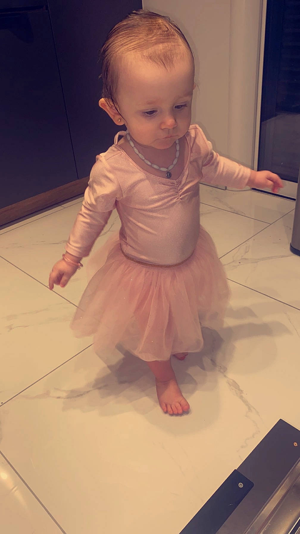 Margot a rejoint le concours — aidez-le/la à gagner de superbes lots ! baby, baby_toddler_clothing, barefoot, cheek, child, floor, flooring, foot, gadget, hardwood, human_leg, knee, person, pink, sitting, skin, sleeve, thumb, toddler, trunk