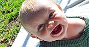 Lukas joined the competition — help win amazing prizes! baby, smiling, outdoor, grass, blanket, green_sweater, happy, face, head, child, person, sunlight, nature, closeup, portrait, infant, cute, cheerful, daylight, skin