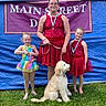 Jaxson is registered to the contest to win money with this photo: award, banner, blue_tarp, child, dance_costume, dog, event, girl, glasses, grass, happy, leash, medal, outdoor, pet, portrait, rainbow_dress, red_dress, smile, standing