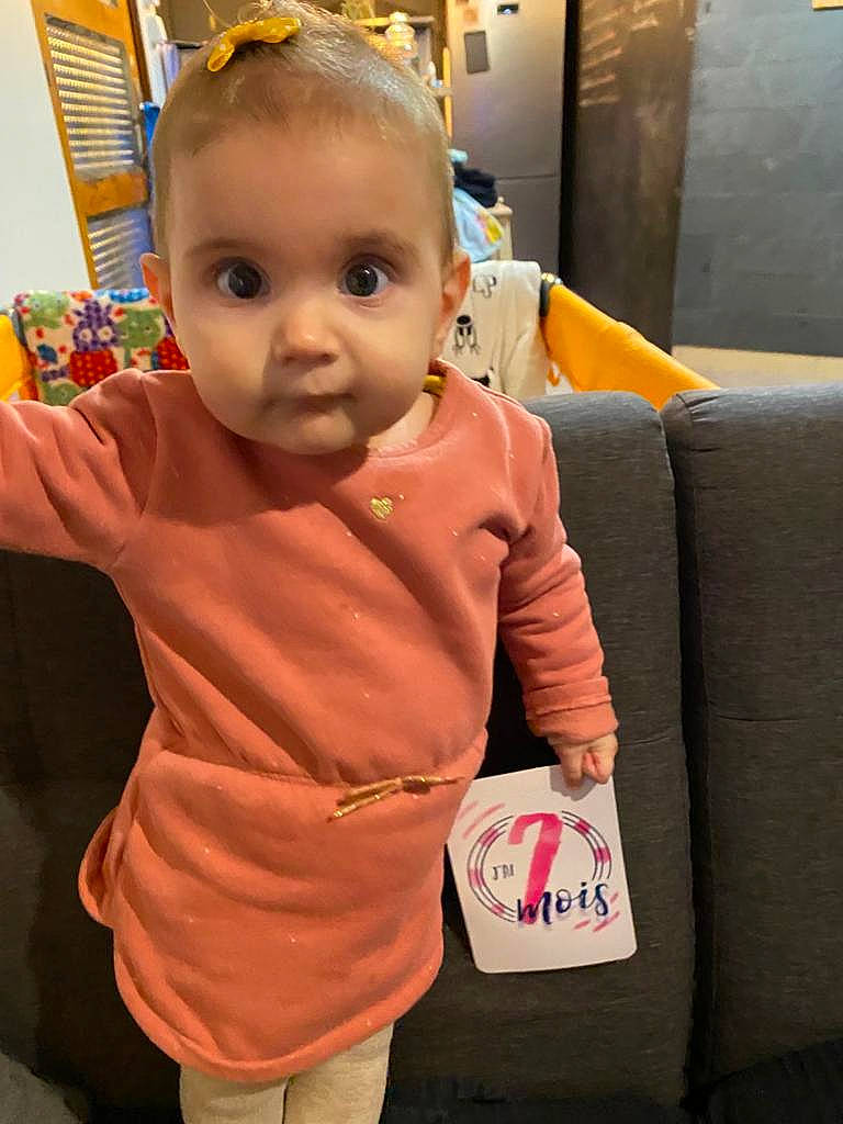 Melina participe au concours pour gagner de l'argent avec cette photo : baby, baby_toddler_clothing, cheek, child, comfort, couch, flooring, fun, iris, nose, orange, person, product, room, skin, sleeve, stuffed_toy, t_shirt, textile, thumb