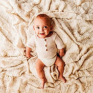 Eden joined the competition — help win amazing prizes! baby, infant, smiling, knitted_clothing, blanket, soft_texture, happy, cute, child, portrait, laying_down, indoor, one_person, human, newborn, face, skin, eyes, expression, warm_color