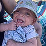 arms, baby, beach, blanket, child, cloth, clothing, cute, dinosaur_pattern, face, happy, hat, headwear, holding, infant, outdoor, person, skin, smile, sunlight