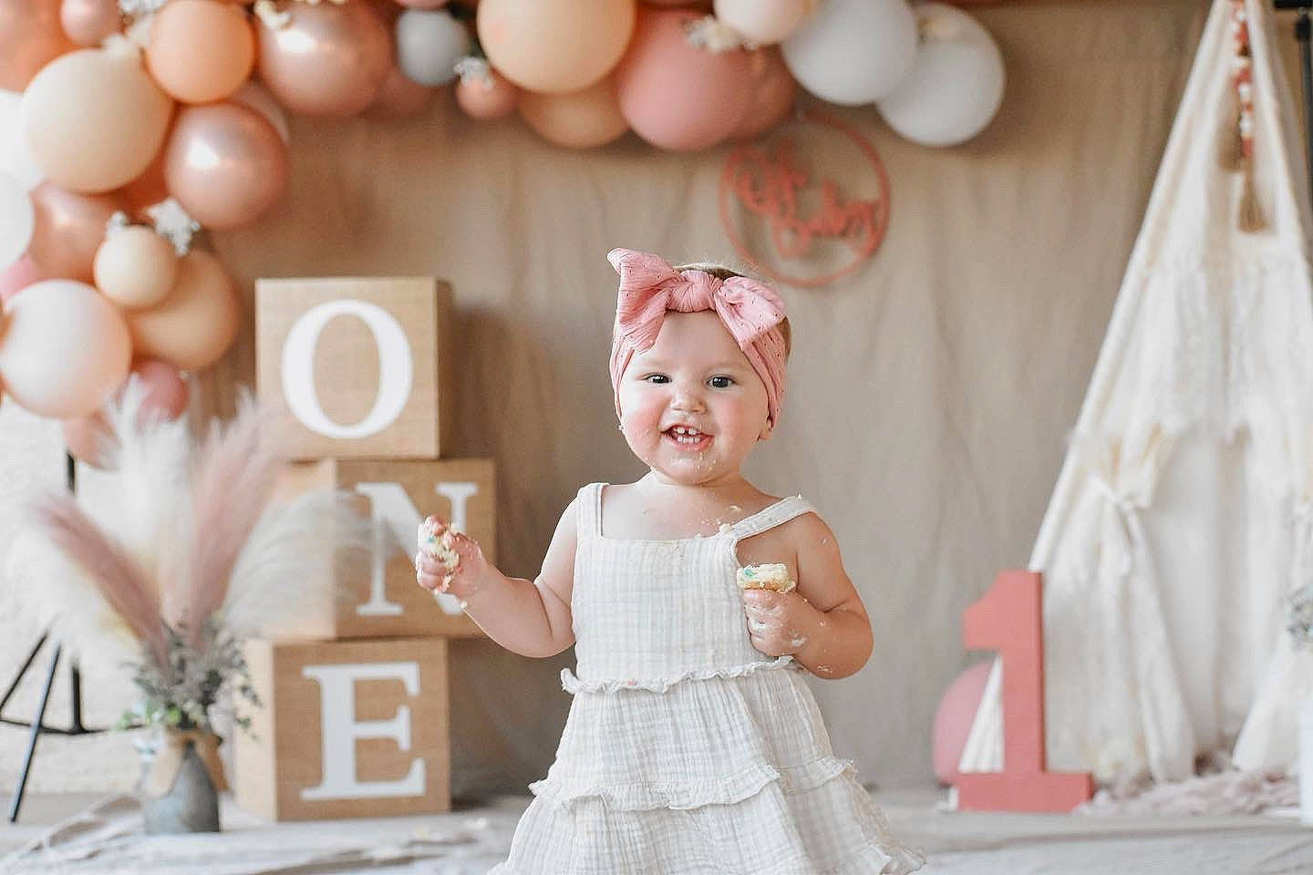 Haisley is registered to the contest to win money with this photo: baby_toddler_clothing, balloon, child, dress, embellishment, event, facial_expression, fun, gown, happy, headpiece, headwear, joy, party_supply, peach, person, photograph, pink, smile, textile