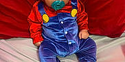 Daniel Alvizures is registered to the contest to win money with this photo: baby, child, pacifier, hood, red_clothing, blue_clothing, sneakers, nike, sitting, indoors, fabric, cute, portrait, young_child, person, footwear, colorful, soft_texture, background, hooded_outfit