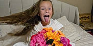Lya a rejoint le concours — aidez-le/la à gagner de superbes lots ! barefoot, bed, blanket, child, colorful, cozy, flower_bouquet, furniture, happy, home, indoor, long_hair, person, pillow, playful, portrait, sitting, smiling, tongue_out, white_robe