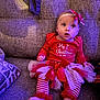 baby, infant, festive_clothing, christmas, red, white, tutu, bow, headband, striped_leggings, couch, seated, indoors, cute, holiday, portrait, child, soft_light, cozy, expression