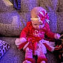 baby, child, christmas, holiday, red_clothing, striped_leggings, bow_headband, tutu, couch, furniture, indoor, festive, cute, sitting, infant, toddler, soft_lighting, cozy, holiday_outfit, motion_blur