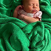 Amelia is registered to the contest to win money with this photo: baby, newborn, sleeping, blanket, green_blanket, soft_texture, infant, wrapped, pink_clothing, peaceful, cozy, portrait, closeup, cute, human, child, resting, warm, indoor, baby_skin