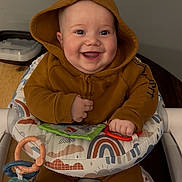 Kash Parsons joined the competition — help win amazing prizes! baby, child, hoodie, smile, happy, baby_seat, toy, rings, soft_book, rainbow_pattern, cloud_pattern, indoor, person, infant, cute, clothing, sitting, playtime, hands, feet
