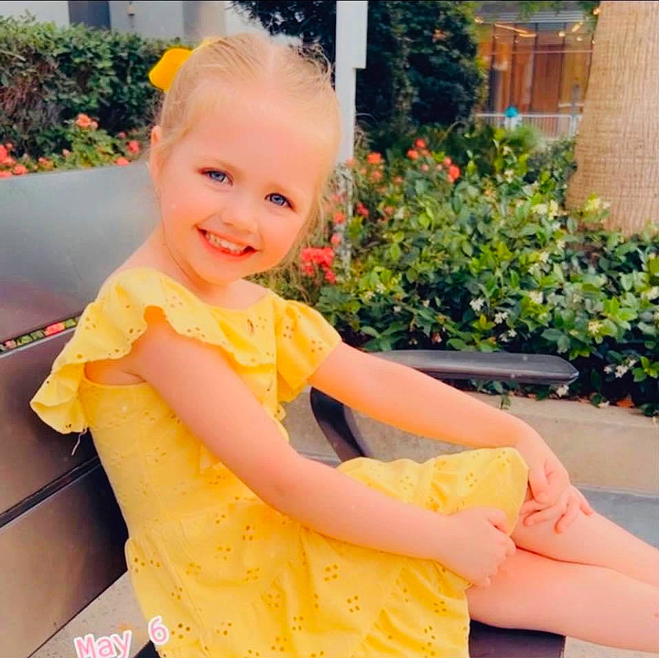 Madeline is registered to the contest to win money with this photo: arm, child, dress, flower, fun, grass, hairstyle, happy, human_leg, joy, leisure, orange, person, pink, plant, shoulder, skin, sleeve, smile, standing