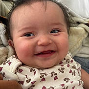 Aimee is registered to the contest to win money with this photo: baby, blanket, child, closeup, cozy, cute, expression, face, flower, hair, happy, indoors, infant, onesie, pattern, person, portrait, skin, smiling, young