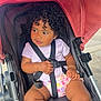 Rhea is registered to the contest to win money with this photo: toddler, child, curly_hair, stroller, baby, diaper, purple_shirt, black_straps, red_canopy, seat, hand, legs, outdoor, side_view, cute, expression, baby_clothing, safety_harness, person, infant