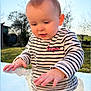 child, baby, toddler, face, hands, reflection, glass_table, striped_shirt, bonjour_text, heart_emoji, outdoor, garden, trees, blue_sky, sunlight, portrait, curiosity, cute, long_sleeves, closeup