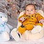 baby, blue, bokeh, child, cozy, cute, decorative, holiday_theme, indoor, infant, plush, portrait, smiling, soft_chair, stuffed_animal, teddy_bear, warm_clothing, white, winter_background, yellow_clothing