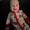 baby, smiling, infant, onesie, clothing, red_trim, heart_pattern, toy, pacifier, happy, face, person, cute, indoors, child, young, lying_down, expression, cheerful, closeup