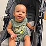 Leonidas joined the competition — help win amazing prizes! baby, child, smiling, stroller, green_outfit, shoes, indoor, happy, cute, infant, person, seated, portrait, young_child, clothing, footwear, expression, baby_toddler, head, face