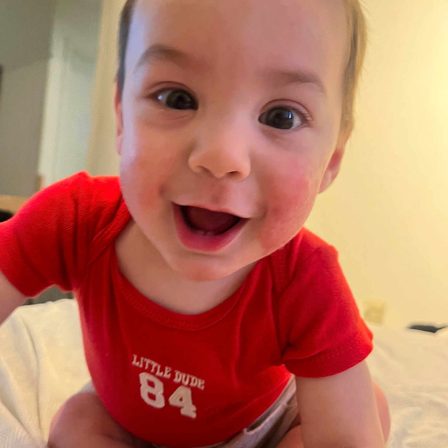 Elieys is registered to the contest to win money with this photo: baby, child, closeup, clothing, crawling, cute, expression, face, happy, indoor, infant, joy, person, playful, red_shirt, sitting, skin, smiling, toddler, young