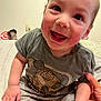 Elieys joined the competition — help win amazing prizes! baby, child, smiling, happy, sitting, tshirt, robot_graphic, rosy_cheeks, hand, bed, indoor, person, cute, infant, casual_clothing, skin, face, expression, young_child, support