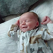 Lucus is registered to the contest to win money with this photo: baby, newborn, sleeping, smiling, onesie, animal_print, pajamas, soft_blanket, bed, infant, cute, peaceful, relaxed, portrait, child, indoors, sleepwear, cozy, face, baby_clothes