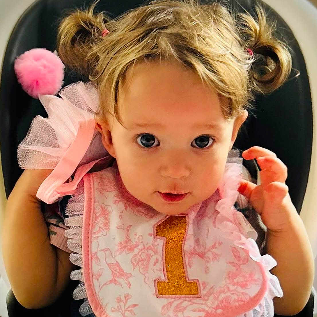 Elaine is registered to the contest to win money with this photo: toddler, child, baby, pigtails, pink_bib, number_one, high_chair, curly_hair, cute, portrait, sitting, face, eyes, clothing, celebration, birthday, indoor, person, young_child, adorable
