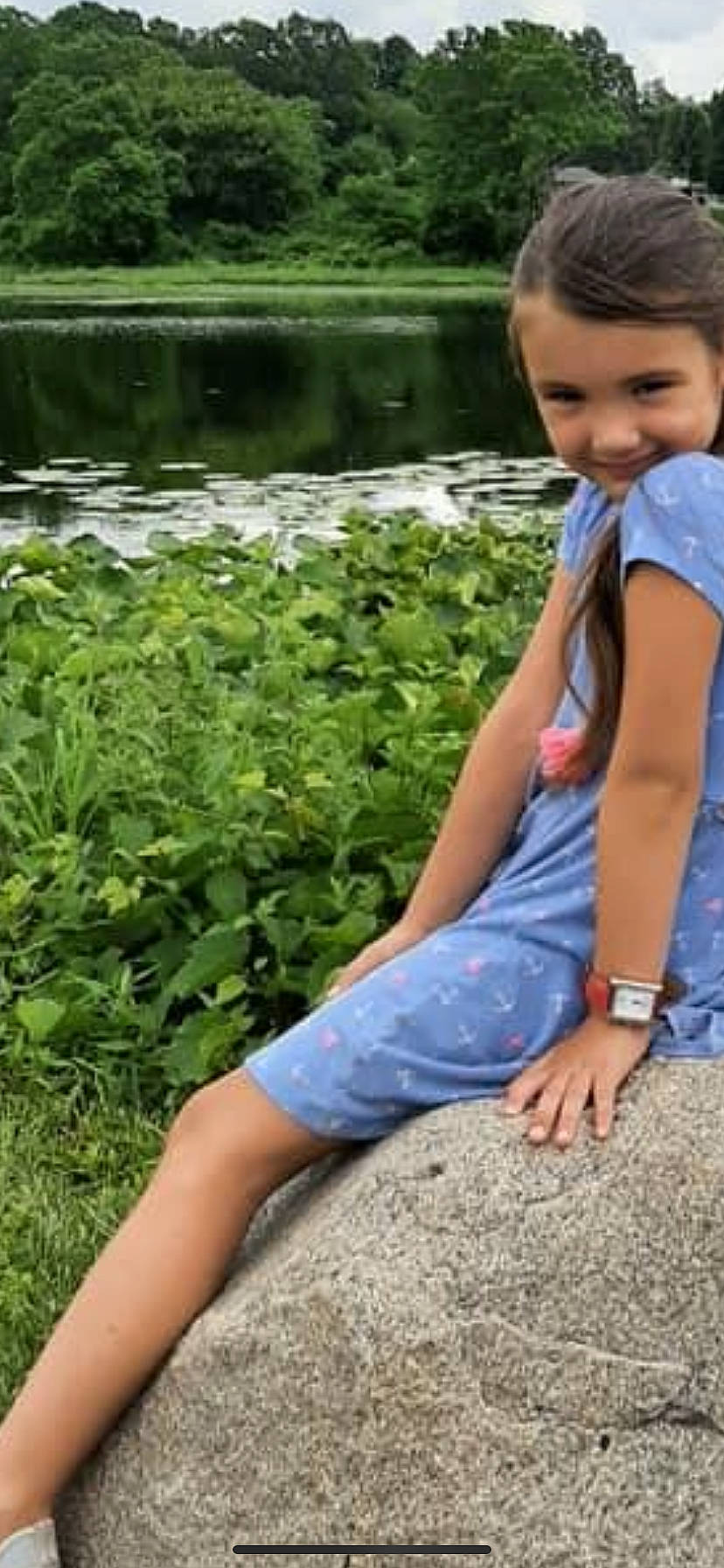 Kendra is registered to the contest to win money with this photo: barefoot, denim, electric_blue, eye, face, grass, grass_family, green, happy, human_leg, joy, lake, landscape, leisure, people_in_nature, person, plant, sitting, summer, thigh