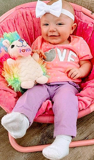 Kenley is registered to the contest to win money with this photo: baby, baby_toddler_clothing, cap, child, comfort, eye, face, green, happy, headwear, lap, magenta, person, pink, red, shoe, sitting, skin, sleeve, smile